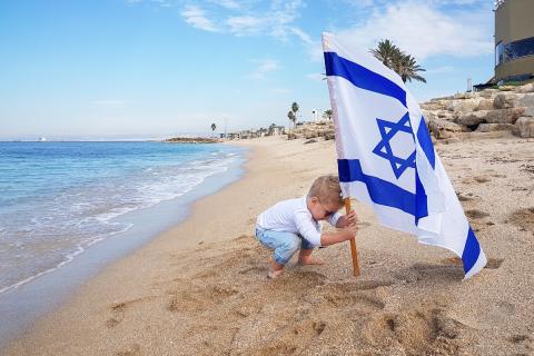 Boy playing the Israeli flag in the beach 